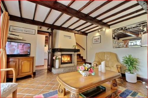 un salon avec une table et une cheminée dans l'établissement Maison de charme à Pléhédel avec jardin, à Pléhédel