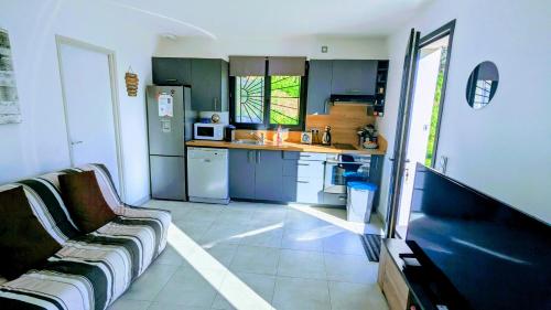 une cuisine avec des armoires bleues et un canapé dans une pièce dans l'établissement Haut de villa 2P, jardin, clim, prise VL Electrique, à Saint-Paul-de-Vence