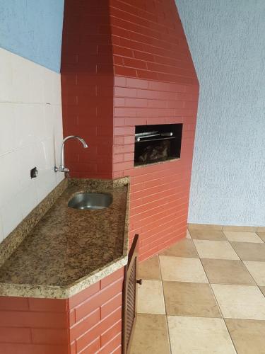 a red brick kitchen with a sink and an oven at INTEIRO com 3 SUITES E PISCINA in Foz do Iguaçu