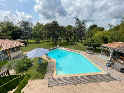 - une vue sur la piscine avec un parasol dans l'établissement Vaste maison familiale en pierres apparentes PROMO SEPTEMBRE, à Gardonne