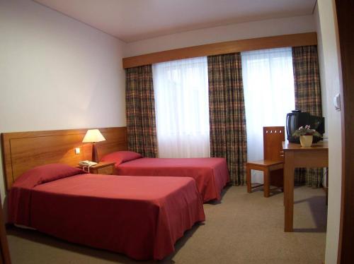 a hotel room with two beds and a television at Hotel Residencial Ermida dos Remédios in Praia da Vitória