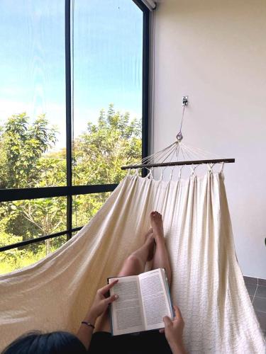 a woman laying in a hammock reading a book at Ecohab el paraíso in Barranca de Upía
