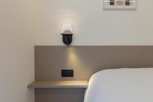a bedroom with a bed and a lamp on a shelf at The Nest - TRILO - WIFI - Box - Cortile - Magnolta in Aprica