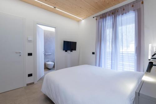 a white bedroom with a bed and a window at The Nest - TRILO - WIFI - Box - Cortile - Magnolta in Aprica