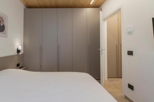 a bedroom with a white bed and a closet at The Nest - TRILO - WIFI - Box - Cortile - Magnolta in Aprica