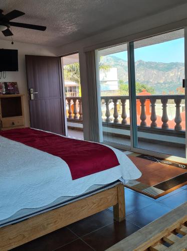 a bedroom with a bed with a view of a balcony at Hotel Leyenda del Tepozteco in Tepoztlán