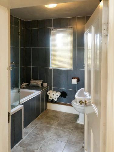 a bathroom with a tub and a toilet and a sink at Kildare in Niton