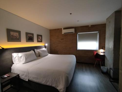 a hotel room with a large bed and a desk at Hotel Quinta Norte Chipichape in Cali