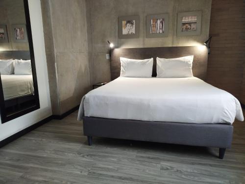 a bedroom with a large bed with white sheets and pillows at Hotel Quinta Norte Chipichape in Cali