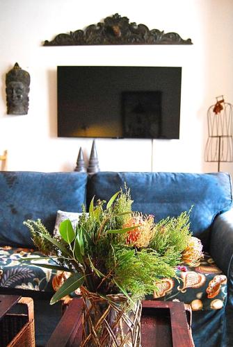 a living room with a blue couch and a table with a plant at Hampton Court Grand Snug Sleeps 6 - Palace walk in East Molesey
