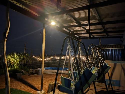 a swings under a roof at night with a city at あさひシーサイドコテージ in Asahi