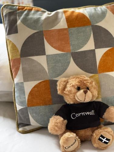a brown teddy bear sitting next to a pillow at PV70 newquay bay resort in Newquay Bay Resort