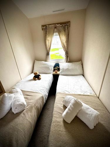 two twin beds in a room with a window at PV70 newquay bay resort in Newquay Bay Resort