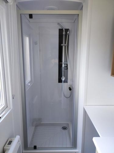 une douche dans une salle de bain avec une porte vitrée dans l'établissement Mobil home, à Pont-Aven