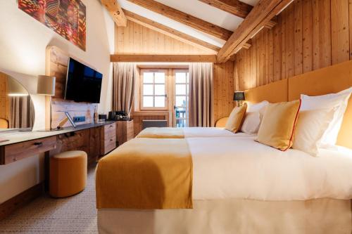 a bedroom with a large bed and a television at La Ferme du Golf in Megève