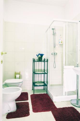 a bathroom with a toilet and a shower with red rugs at Torrebianca in Trieste