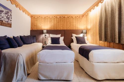 two beds in a room with wooden walls at La Ferme du Golf in Megève