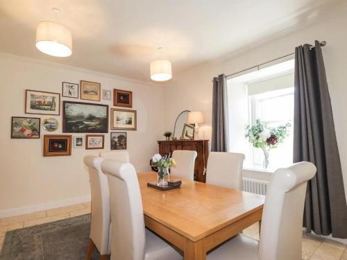 a dining room with a wooden table and white chairs at Mary Ann Villa in Inverness