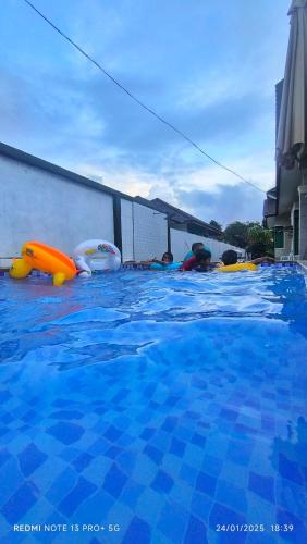 a swimming pool with some people in the water at Tiffana Homestay in Kampong Ayer Terjun