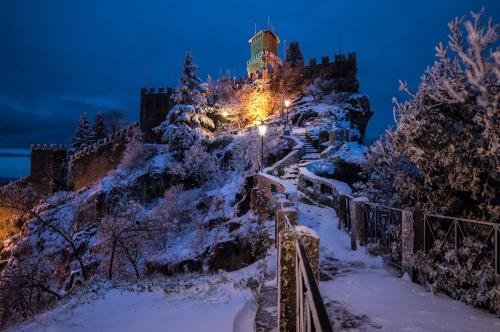 a castle on a mountain in the snow at night at Hotel La Rocca in San Marino