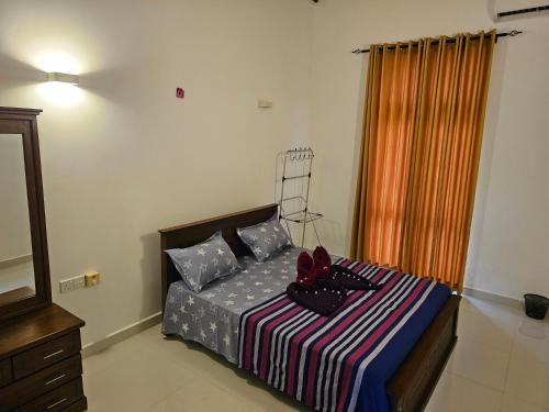 a bedroom with a bed with a striped blanket at Bevons Place in Piliyandala