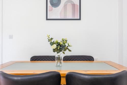 a vase of flowers on a table with two chairs at PrimeStay Residence in Slough