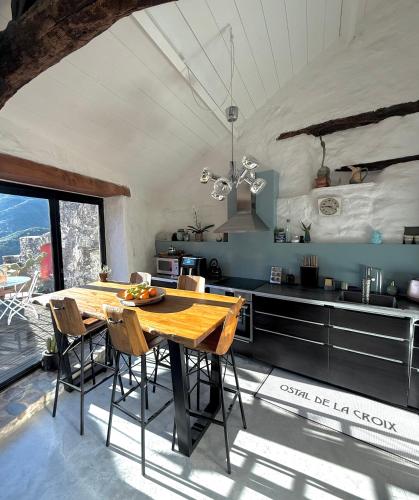 une cuisine avec une table en bois et quelques chaises dans l'établissement Ostal de la Croix Vieussan, à Vieussan