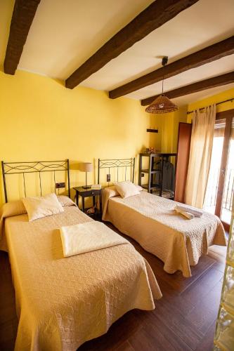 two beds in a room with yellow walls at Casa Rural El Planet de Maella Casa rural en Castellon Casa rural con Jacuzzi Casa rural en Xert Casa rural cerca de Morella in Xert