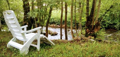 a white rocking chair sitting in the grass next to a stream at Shui wu, la casita del agua in Geras