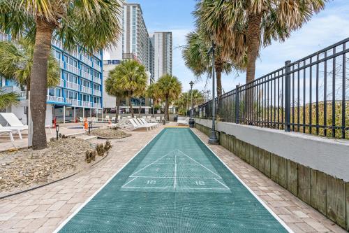 a green basketball court with palm trees and buildings at Yachtsman Oceanfront Resort in Myrtle Beach