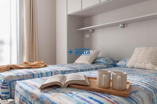 two beds with a book and two mugs on them at Wave Island in Lido di Jesolo