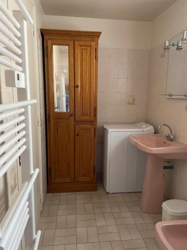 La salle de bains est pourvue d'un lavabo et d'une porte en bois. dans l'établissement Maison cozy la casa de Coronata Châteaux-Beauval, à Gièvres