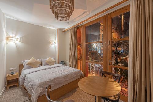 a bedroom with a bed and a table and a window at Palm Tbilisi Boutique Hotel in Tbilisi City