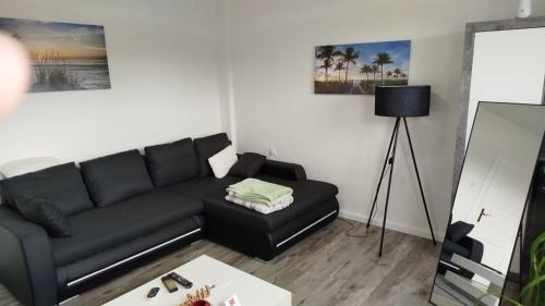a living room with a black couch and a table at Schöne Ferienwohnung/Pendlerwohnung in Uelzen