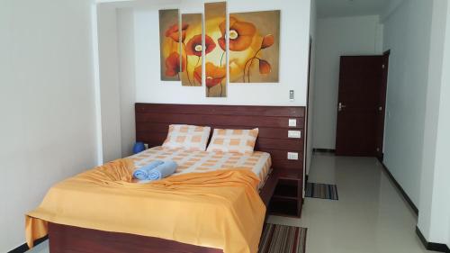 a bedroom with a bed with two paintings on the wall at The Den Guest House in Hikkaduwa