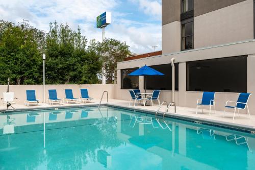 a swimming pool with chairs and an umbrella at Holiday Inn Express Tallahassee by IHG in Tallahassee