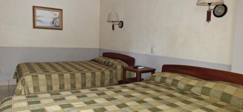 a room with two beds and a table in it at Hotel Playa Bonita Tela in Tela