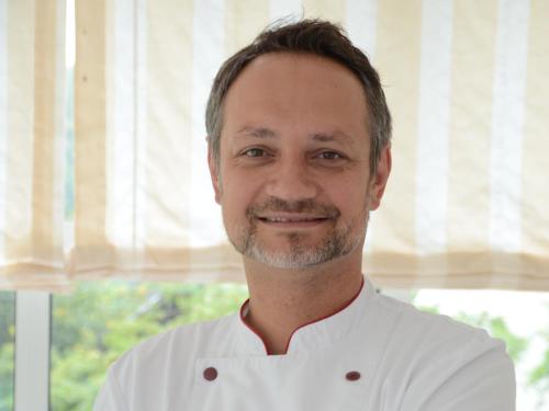 a man in a chefs outfit smiles at the camera at Bad Schauenburg in Liestal