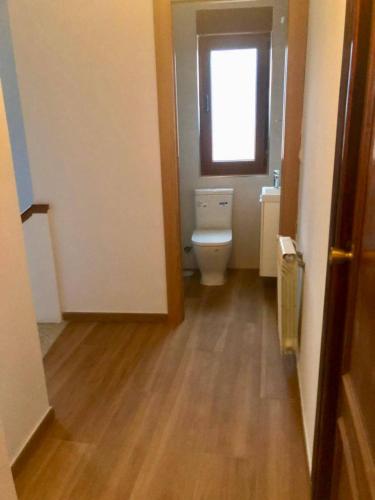 Un baño con inodoro y ventana. en Casa con jardín a pie de playa y montaña, en Panes