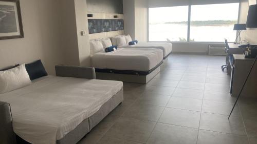 a hotel room with three beds and a couch at DoubleTree by Hilton Guayaquil in Guayaquil