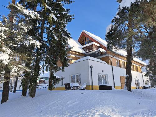 a house in the snow with trees in the foreground at Apartmany Riviera 505 in Lipno nad Vltavou