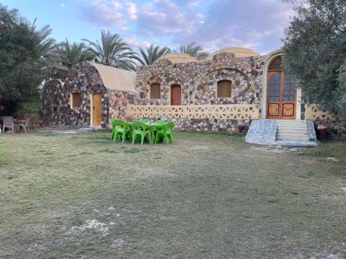 a building with four green tables in front of it at Ahmed Safari Camp in Bawiti