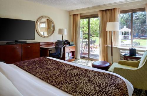 a hotel room with a bed and a desk and a television at Detroit Marriott Livonia in Livonia