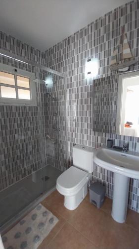 a bathroom with a white toilet and a sink at Maison vue mer avec piscine in Caleta De Fuste