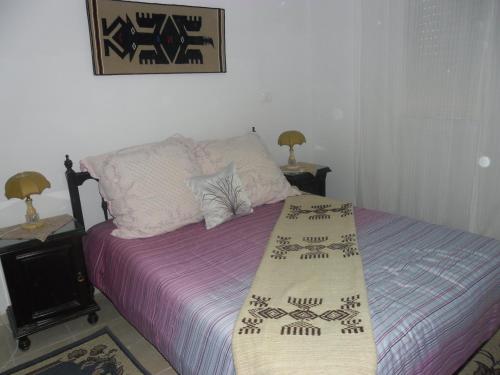a bedroom with a bed with purple sheets and two lamps at Apartment Essayadi Residence in Port El Kantaoui