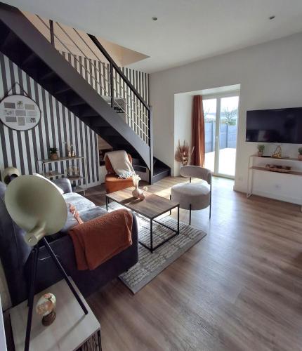 a living room with a couch and a staircase at Gite La maison du 37 avec terrasse et jardinet in Breteil