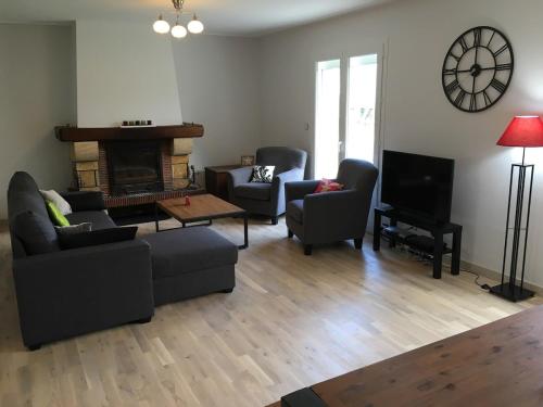 a living room with a couch and chairs and a television at Venez vous ressourcer au calme in Locmaria-Grand-Champ