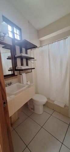 a bathroom with a sink and a toilet and a window at Hotel Playa Bonita Tela in Tela