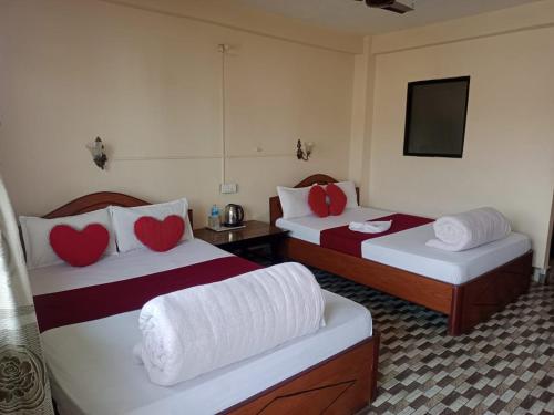 a hotel room with two beds with red heart pillows at Sauraha Inn in Sauraha