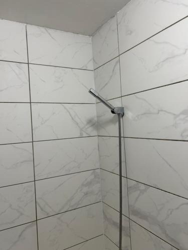 a white tiled wall with a shower in a bathroom at NICE HOUSE Families contractors in Birmingham